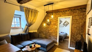 A loft-style living room with a brick wall, a loft bed, a sofa, and a coffee table. - Opera apartments  (Banska Stiavnica)