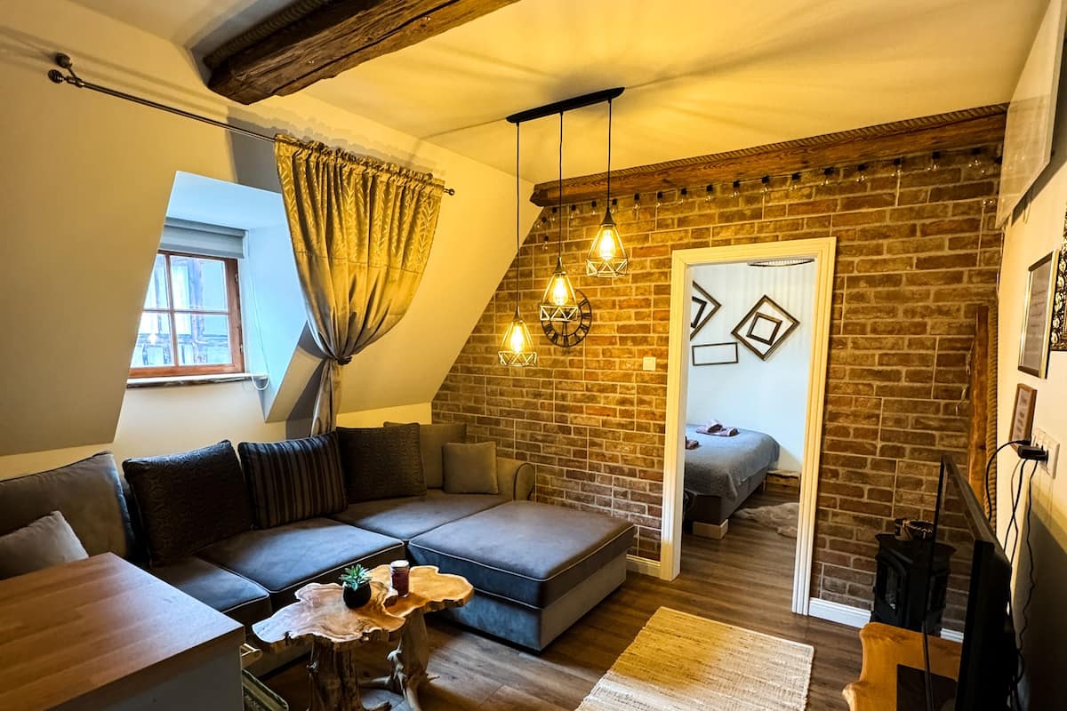 A loft-style living room with a brick wall, a loft bed, a sofa, and a coffee table.