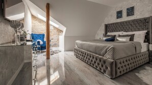 A modern bedroom with a large bed, a stone wall, and a skylight. - Opera apartments  (Banska Stiavnica)
