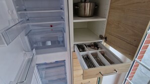 A kitchen with a built-in refrigerator, a wooden cabinet, and a tiled floor. - Beautiful vacation apartment (1) on the north beach with WiFi for up to 4 people from 9 € pP (Putgarten)