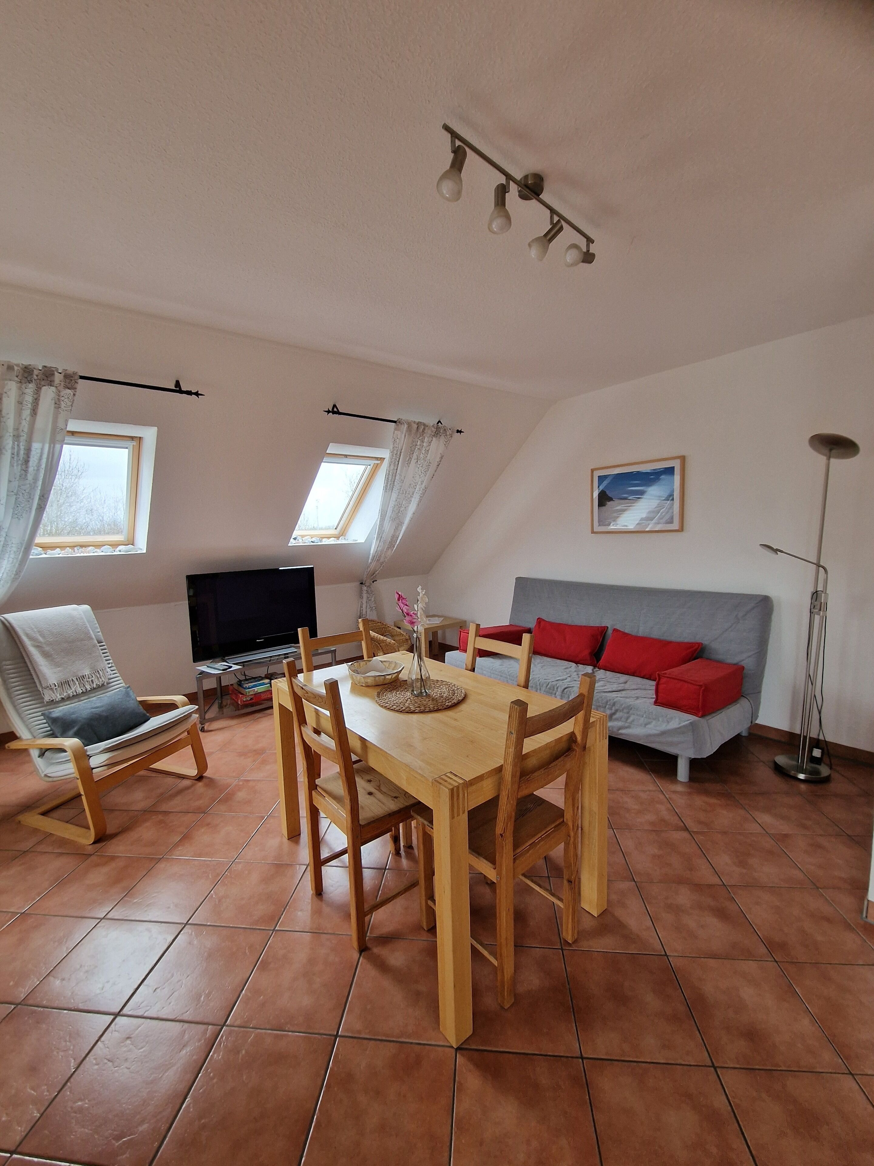 Un salon confortable avec une table à manger, des chaises, un canapé, un téléviseur et un lampadaire.