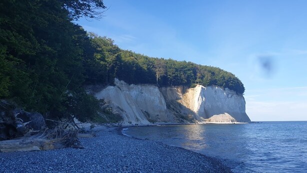 A coastal landscape with a rocky beach, a cliff with vegetation, and the sea. - Beautiful vacation apartment (1) on the north beach with WiFi for up to 4 people from 9 € pP (Putgarten)