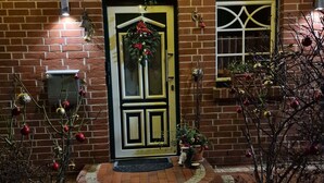 A brick building with a central entrance door decorated with a wreath and red ornaments. There are two windows with decorative frames, and a small step leading up to the door. - Beautiful vacation apartment (1) on the north beach with WiFi for up to 4 people from 9 € pP (Putgarten)