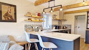 A modern kitchen with a central island, bar stools, and a wooden ceiling. - The Stables, Wickham -  a barn conversion that sleeps 2 guests  in 1 bedroom (Shedfield)