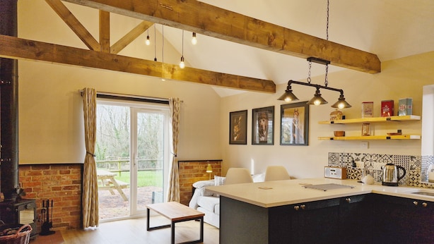 A modern kitchen with a large island, wooden beams, and a view to the outside. - The Stables, Wickham -  a barn conversion that sleeps 2 guests  in 1 bedroom (Shedfield)