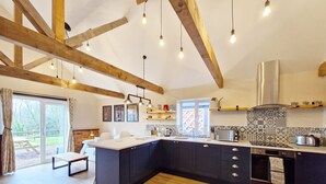 A modern kitchen with dark cabinets, a large island, and pendant lighting. - The Stables, Wickham -  a barn conversion that sleeps 2 guests  in 1 bedroom (Shedfield)