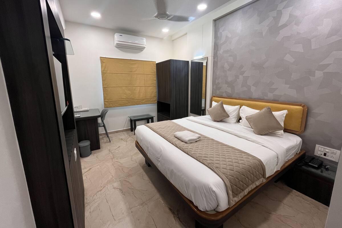 Une chambre d’hôtel moderne équipée d’un lit, d’une table de chevet et d’un bureau avec une chaise.