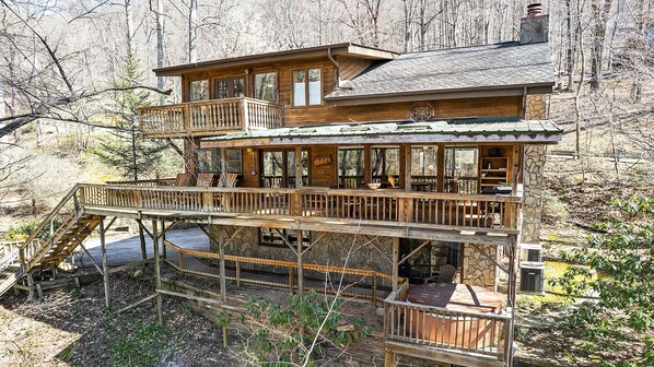 Une cabane en bois à deux étages, dotée d’un balcon et entourée d’arbres.