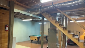 A basement with a pool table, a fire extinguisher, a staircase, and a large metal structure. - Bucksnort Lodge- Blue Ridge GA (Blue Ridge)
