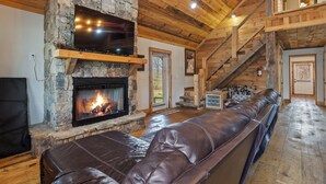Una sala de estar acogedora con una chimenea de piedra, un sofá de cuero y un techo de madera.