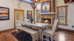 Un intérieur rustique avec une cheminée en pierre, des meubles en bois et des œuvres d’art encadrées accrochées aux murs.