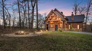 Un chalet rustique doté d’une cheminée en pierre, de poutres en bois et d’un mur de pierre qui entoure la propriété.