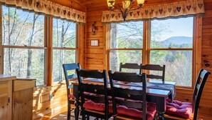A wooden cabin with a dining table and chairs, large windows, and a chandelier. - Hog Heaven - Cherry Log GA (Cherry Log)