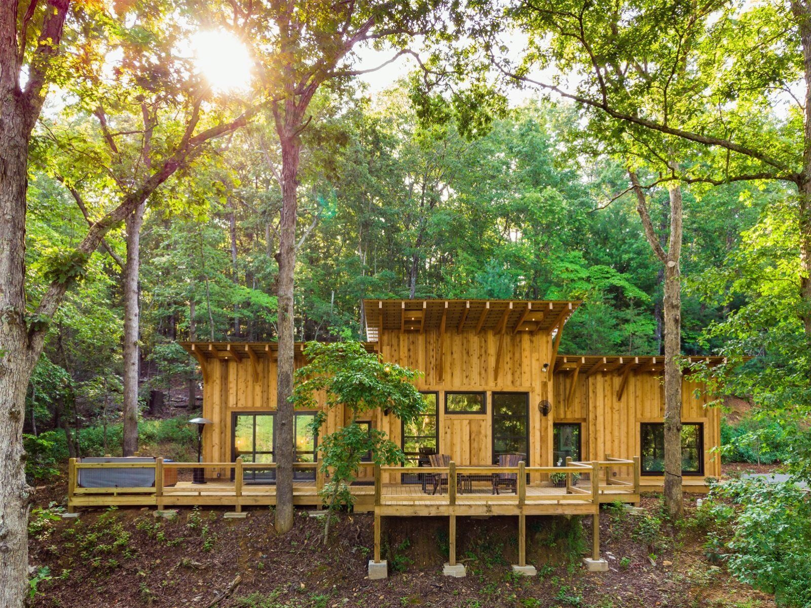 Une cabane en bois dotée d’une terrasse, entourée d’arbres.