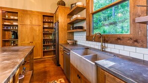 A kitchen with wooden cabinets, a stainless steel sink, and a window with a forest view. - Sugar Shack - Blue Ridge GA (Blue Ridge)