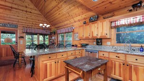 L’intérieur d’un chalet en bois comprend une cuisine dotée d’un comptoir en granit, de meubles en bois et d’un coin repas avec des chaises.