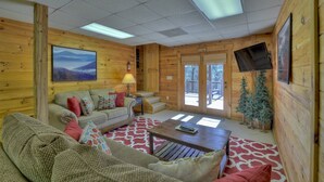 A cozy cabin interior with a sofa, a coffee table, a lamp, and a television mounted on the wall. - A Walk In The Clouds- Cherry Log GA (Cherry Log)