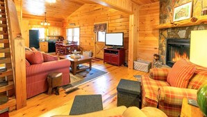 Een gezellig interieur van een vakantiehuis met een woonkamer, eethoek en open haard.