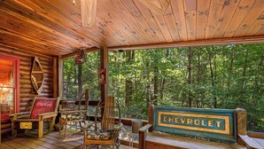 Une cabane en bois avec une véranda, des fauteuils à bascule et une enseigne Chevrolet.