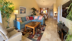 A living room with a blue sofa, a wooden coffee table, and a patterned rug. - Charming Sunset views (Sarasota)