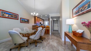 A dining area with a glass table and chairs, a wooden bench with a basket, and framed pictures on the walls. - Charming Sunset views (Sarasota)