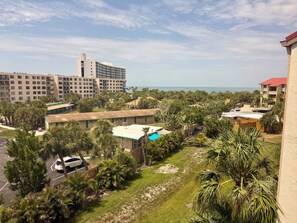A resort with a pool, palm trees, and a view of the ocean.