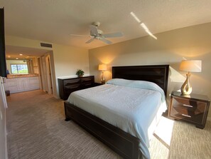 Relax in this inviting hotel room featuring a large bed, ceiling fan, and comfortable seating areas.