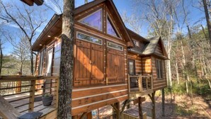 A wooden cabin with a deck, large windows, and a chimney. - Misty Mountain Treehouse- Blue Ridge GA (Morganton)