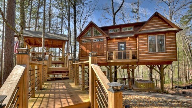 A wooden cabin with a deck and a covered area, surrounded by trees. - Misty Mountain Treehouse- Blue Ridge GA (Morganton)