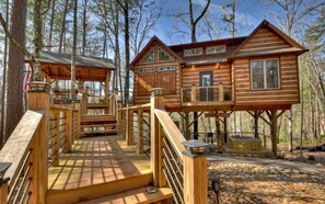 A wooden cabin with a deck and a covered area, surrounded by trees. - Misty Mountain Treehouse- Blue Ridge GA (Morganton)
