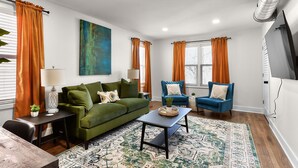 A modern living room with a green sofa, blue armchair, and a patterned rug.