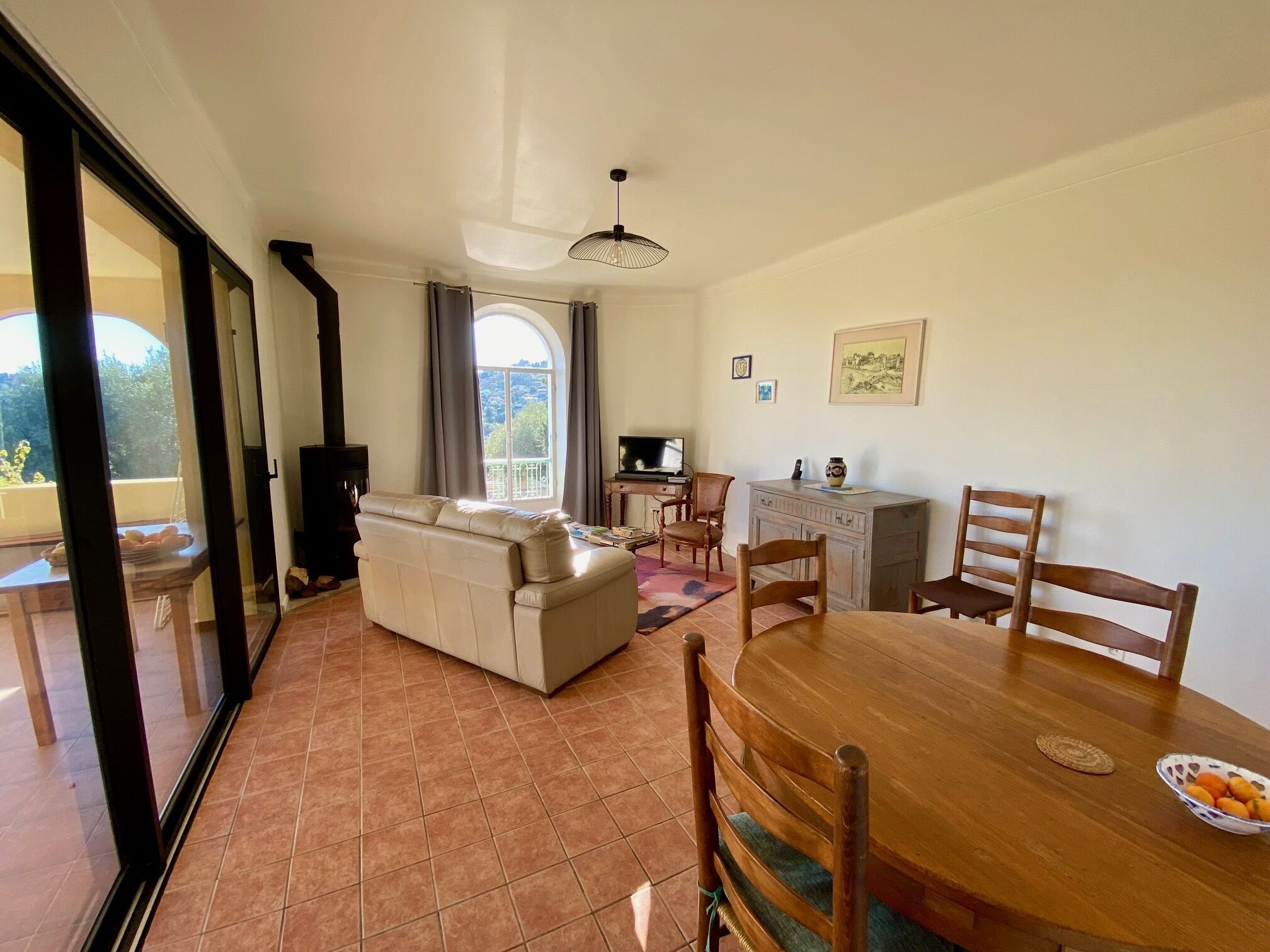 A living room with a sofa, dining table, chairs, and a TV.