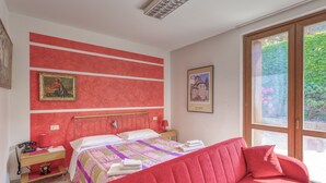 Een slaapkamer met een bed, een rode bank, een bureau met telefoon en ingelijste foto's aan de muur.