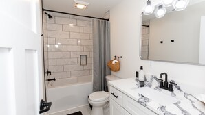 A modern bathroom with a bathtub, toilet, and vanity with a mirror. - Sleeps 8! New Condo Near Downtown Waterfront (Sandusky)