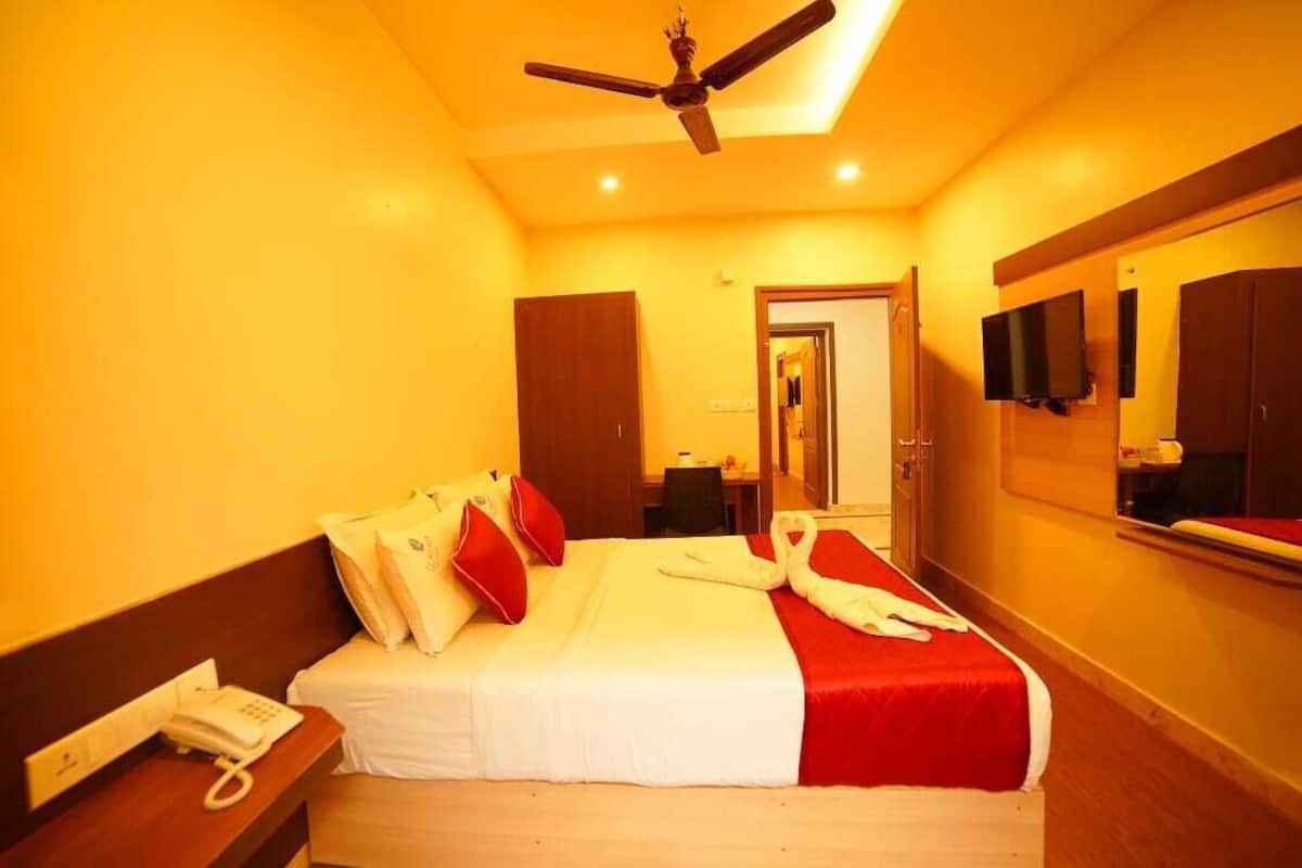 Ein Hotelzimmer mit Bett, Telefon, Deckenventilator, Fernseher und Spiegel.