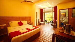 A hotel room with a bed, a ceiling fan, a balcony with chairs, and a breakfast setup.