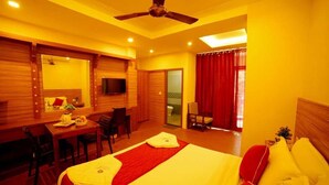 A hotel room with a bed, a desk, a chair, a television, and a ceiling fan.