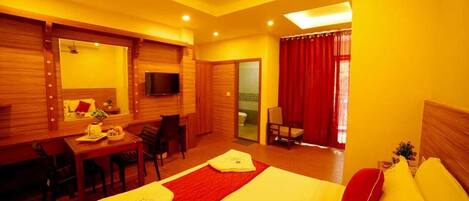 A hotel room with a bed, a desk, a chair, a television, and a ceiling fan.