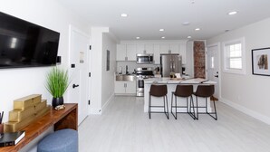 Una cocina moderna con armarios blancos, electrodomésticos de acero inoxidable y una isla central con taburetes de bar.