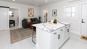 A modern kitchen with white cabinets, a marble countertop, and a small island. - Sleeps 6! Modern & Upgraded Boutique Condo (Sandusky)