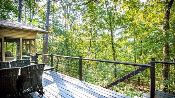 A wooden deck with wicker chairs and a covered seating area overlooking a forest. - 01105 - 5 Montserrat Lane (Hot Springs)