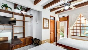 A room with a bed, a desk, a TV, and a ceiling fan. - Poseidon Party Hotel In Downtown (Jacó)