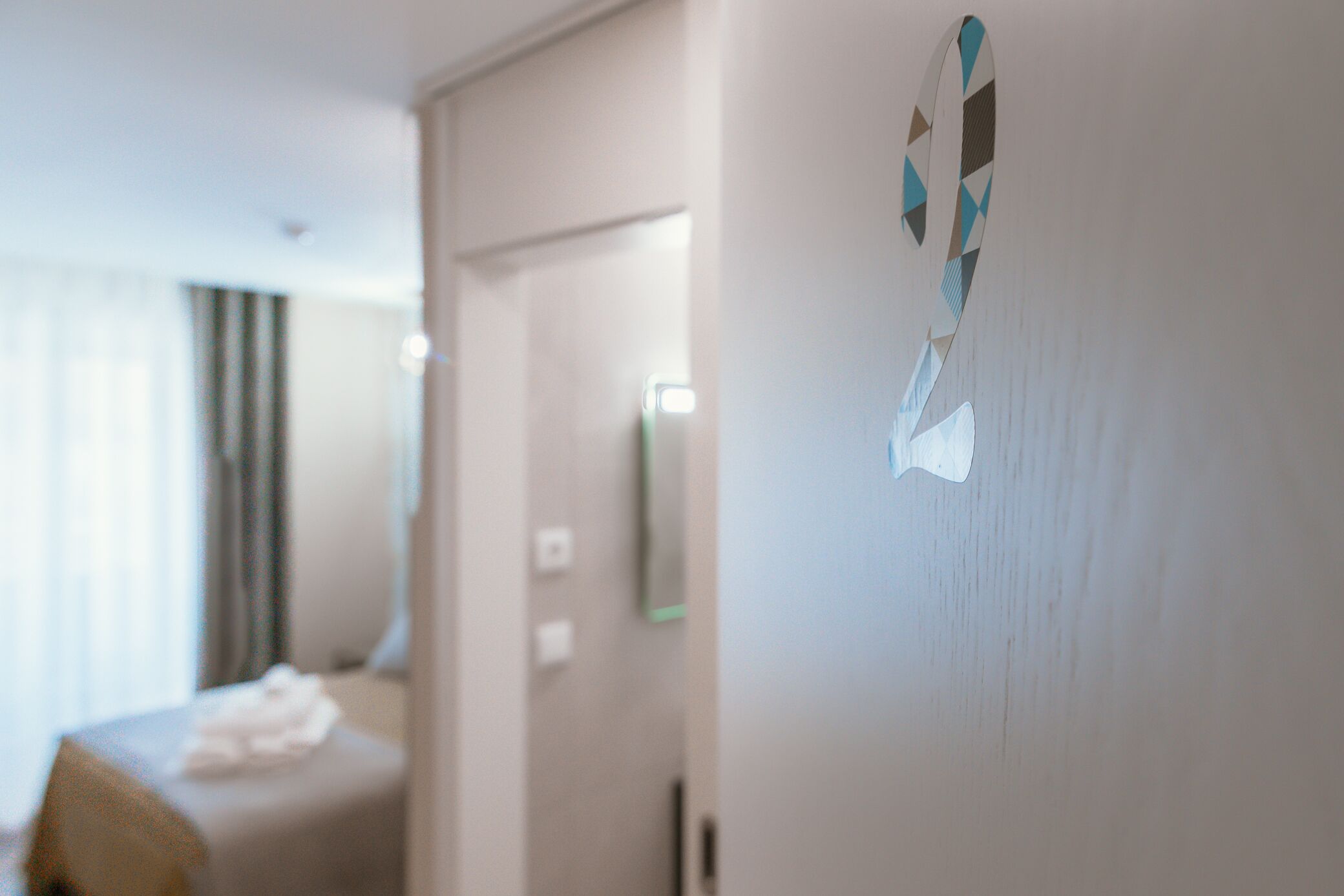 Une chambre d’hôtel avec un lit, une table de chevet et un luminaire fixé au mur.