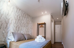 Un dormitorio con cama, almohadas, mesita de noche y un perchero en la pared.