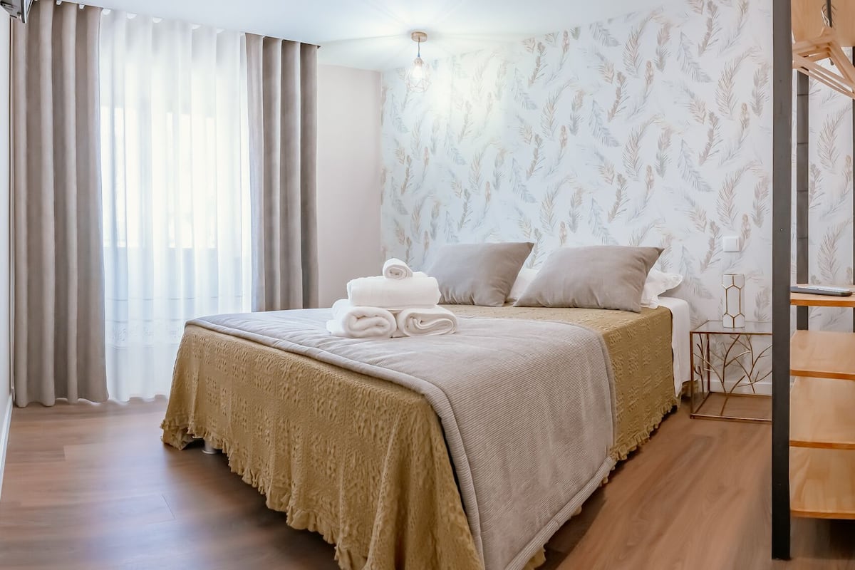 Une chambre d’hôtel avec un lit, une table de chevet en bois, un miroir et un espace douche.