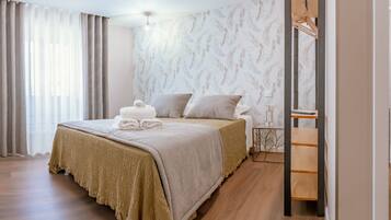 Quarto de hotel com uma cama, mesa de cabeceira de madeira, espelho e área de chuveiro.