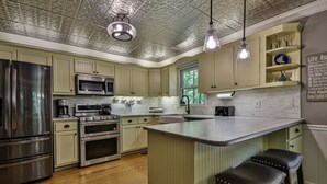 Uma cozinha com eletrodomésticos de aço inoxidável, uma ilha central, banquetas e iluminação pendente.