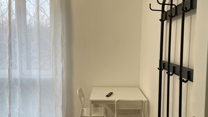 A room with a white table, a white chair, a black bench, a wall-mounted air conditioner, and a coat rack. - Casa di Silvia Appartamento a soli 20 Minuti a piedi dal suggestivo Lago di Como (Como)
