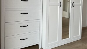 A white wardrobe with multiple drawers and a mirrored closet door. - Casa di Silvia Appartamento a soli 20 Minuti a piedi dal suggestivo Lago di Como (Como)