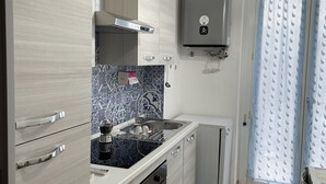 A modern kitchen with light wood cabinets, a patterned backsplash, a built-in oven, and a small refrigerator. - Casa di Silvia Appartamento a soli 20 Minuti a piedi dal suggestivo Lago di Como (Como)